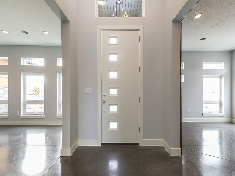 Exempel på en mellanstor modern foajé, med grå väggar, betonggolv, en enkeldörr och en vit dörr