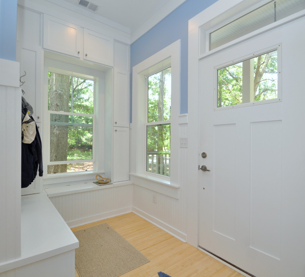 Idée de décoration pour une petite entrée avec un vestiaire, un mur bleu, parquet en bambou, une porte simple et une porte blanche.
