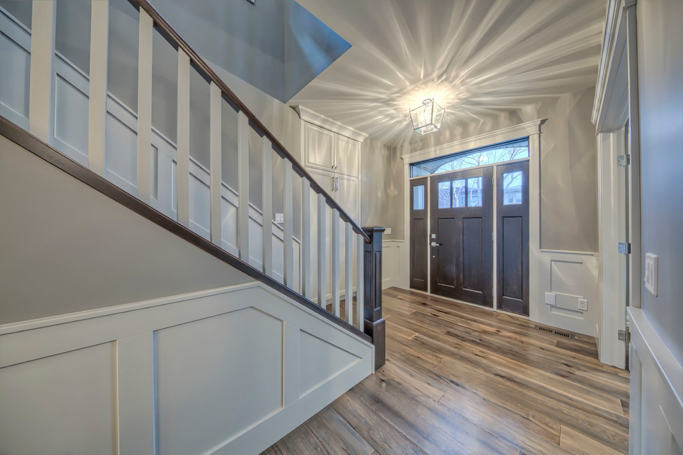 Mid-sized transitional medium tone wood floor and brown floor entryway photo in Calgary with gray walls and a dark wood front door