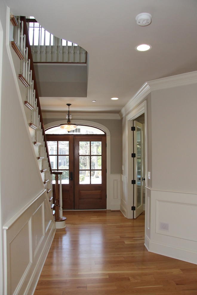 Example of a large transitional medium tone wood floor entryway design in DC Metro with beige walls and a dark wood front door