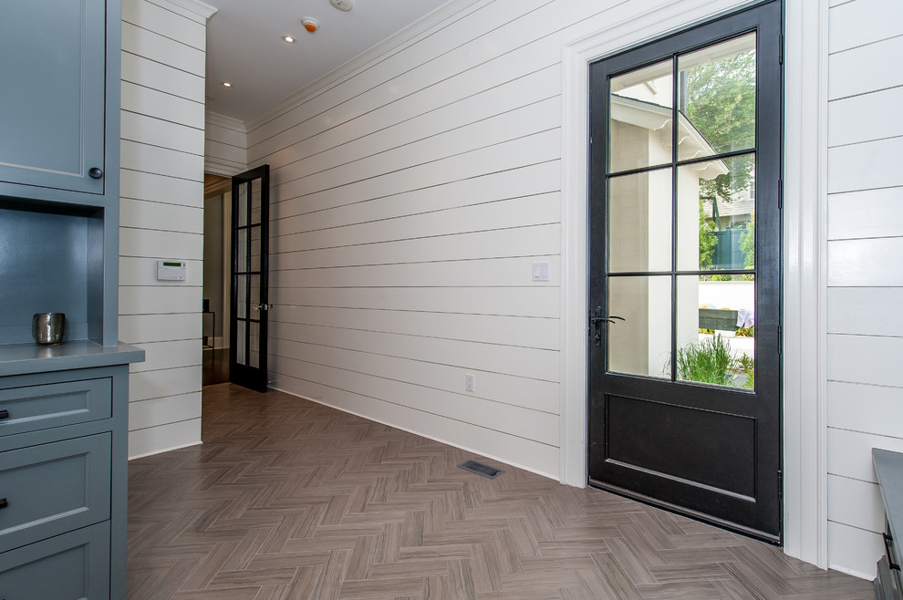 Cette photo montre une grande entrée tendance avec un vestiaire, un mur blanc, un sol en carrelage de céramique, une porte simple et une porte noire.