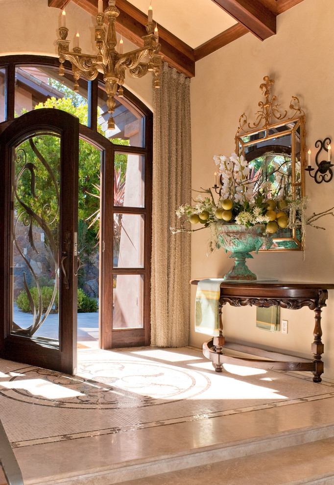 他の地域にあるラグジュアリーな広い地中海スタイルのおしゃれな玄関ドア (ベージュの壁、大理石の床、濃色木目調のドア) の写真