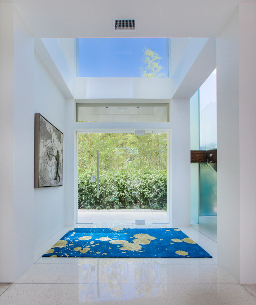 Inspiration for a large contemporary travertine floor entryway remodel in Los Angeles with white walls and a glass front door