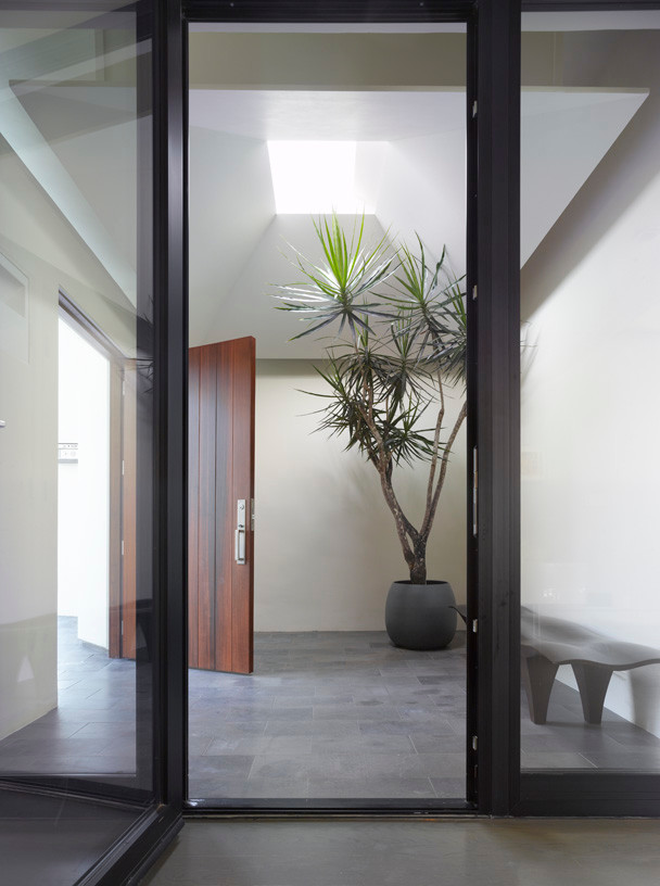 Mittelgroßer Moderner Eingang mit Vestibül, weißer Wandfarbe, Betonboden, Einzeltür, hellbrauner Holzhaustür und grauem Boden in Los Angeles