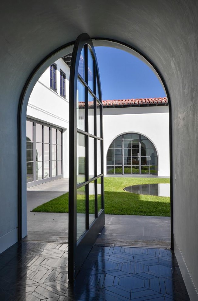 Entryway - huge mediterranean concrete floor entryway idea in Los Angeles with white walls