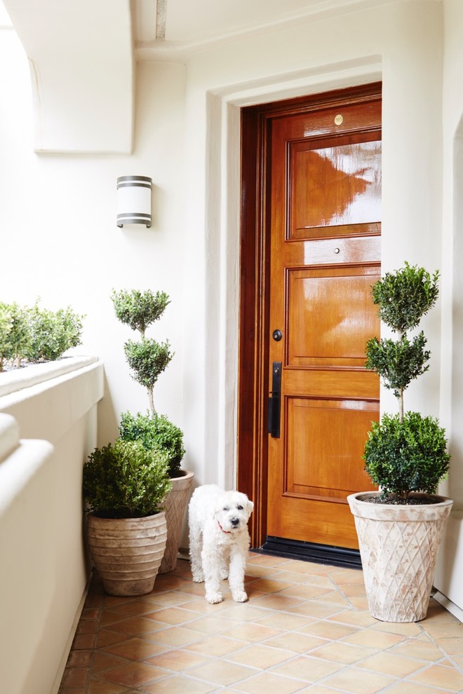 Mittelgroße Mediterrane Haustür mit beiger Wandfarbe, Terrakottaboden, Einzeltür, hellbrauner Holzhaustür und braunem Boden in Los Angeles
