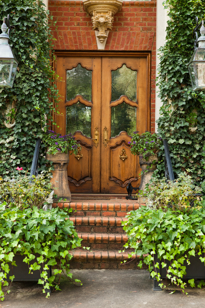 Cette image montre une porte d'entrée victorienne avec une porte double et une porte en bois brun.
