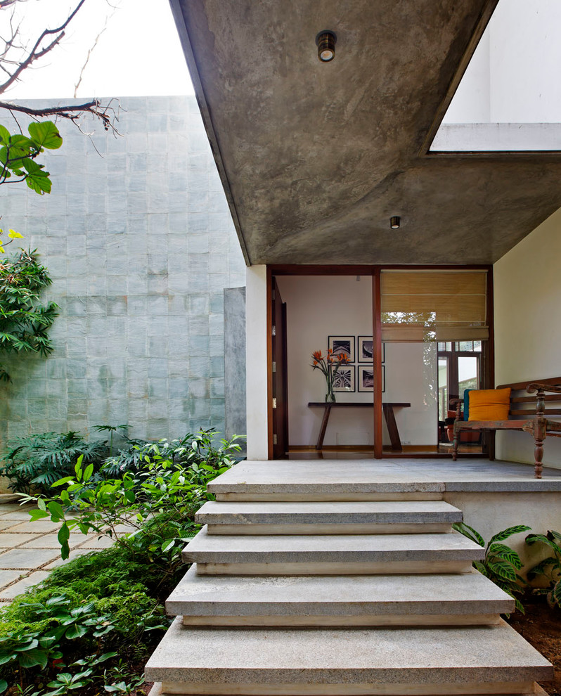 Modern inredning av en ingång och ytterdörr, med vita väggar, betonggolv, en enkeldörr och mellanmörk trädörr