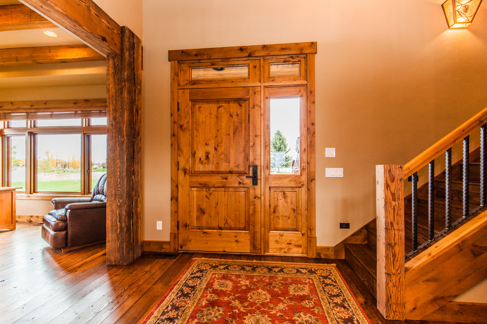 Ispirazione per un ingresso rustico di medie dimensioni con pareti beige, pavimento in legno massello medio, una porta singola e una porta in legno bruno