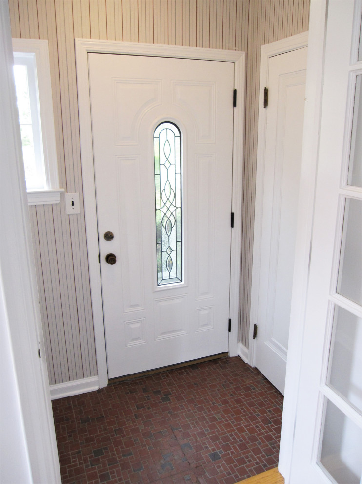 Cette image montre un petit vestibule traditionnel avec un sol en carrelage de céramique, une porte simple, une porte blanche, un sol rouge et du papier peint.