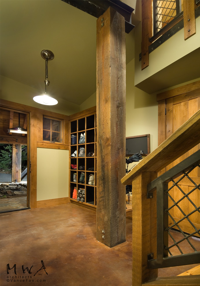 Cette photo montre une entrée tendance avec un vestiaire, sol en béton ciré, une porte simple, une porte en bois clair, un sol marron et un mur vert.