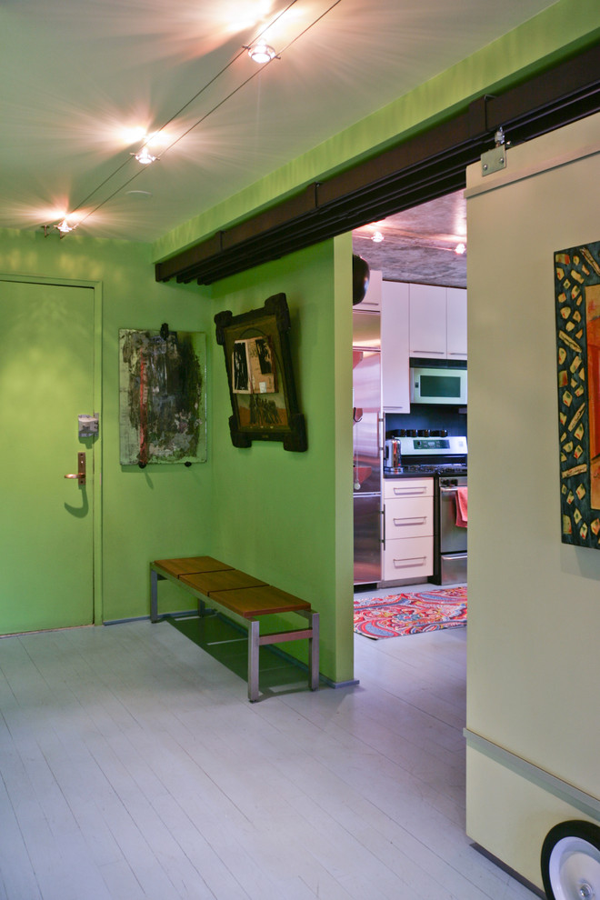 Cette image montre une entrée bohème avec un mur vert et parquet peint.