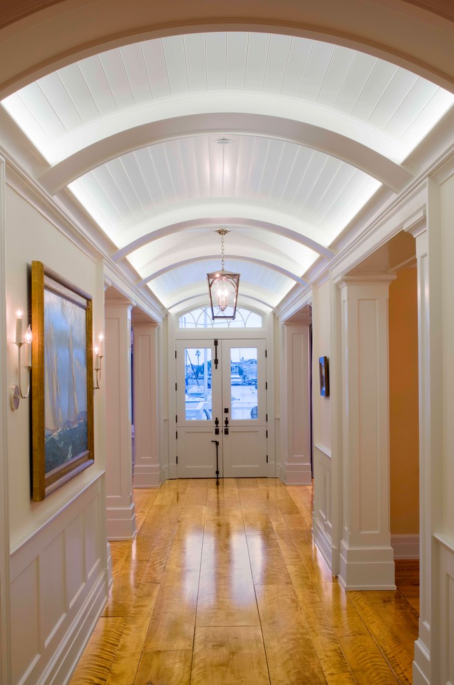 Immagine di un ingresso o corridoio tradizionale con pareti bianche, pavimento in legno massello medio, una porta a due ante e una porta bianca