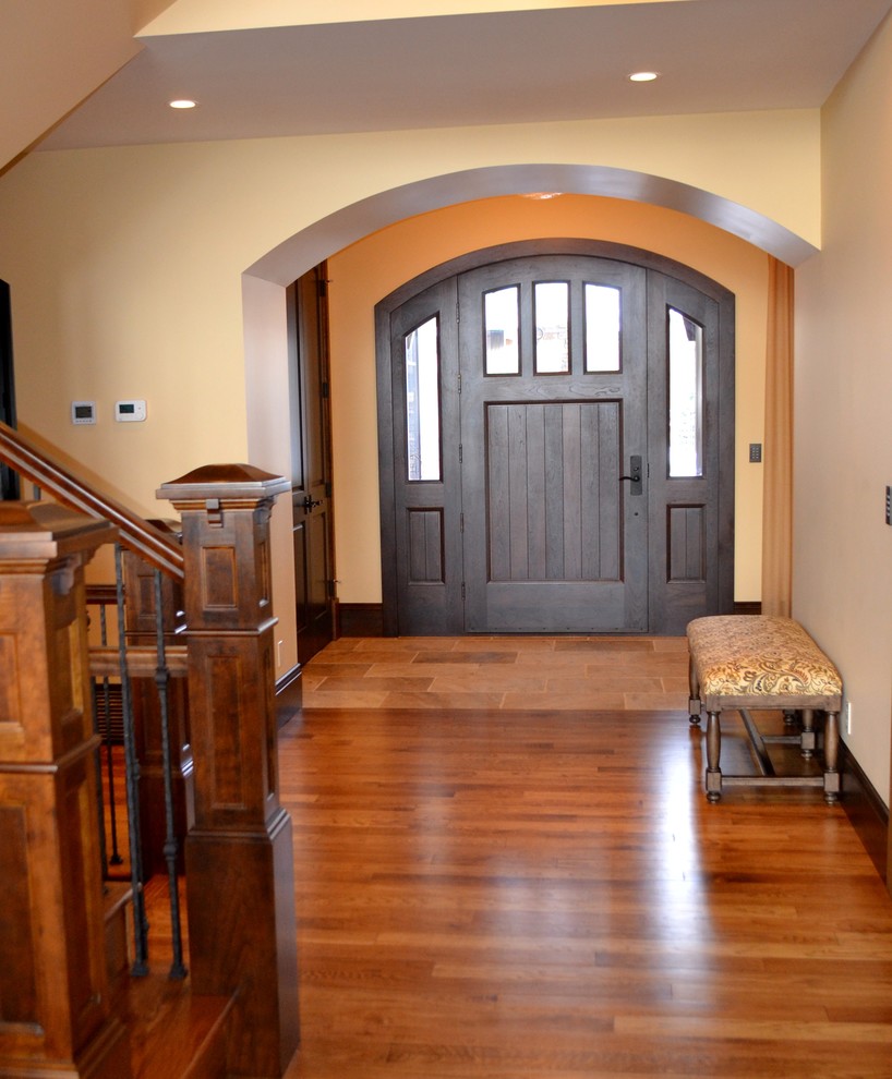 Inspiration for a mid-sized timeless dark wood floor and brown floor entryway remodel in Calgary with yellow walls and a dark wood front door