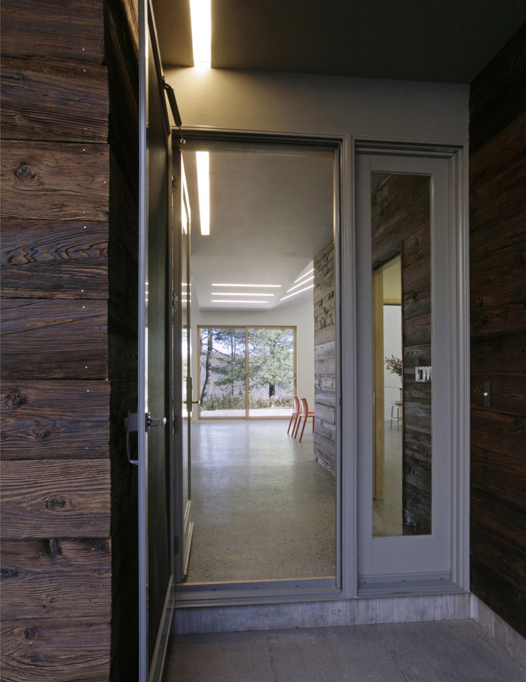 Photo of a medium sized modern entrance in New York with brown walls, concrete flooring, a single front door and a glass front door.