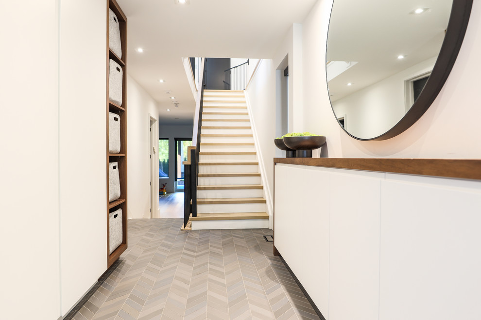 Foto di un corridoio minimal di medie dimensioni con pareti bianche, pavimento in gres porcellanato, una porta singola, una porta in legno bruno e pavimento grigio