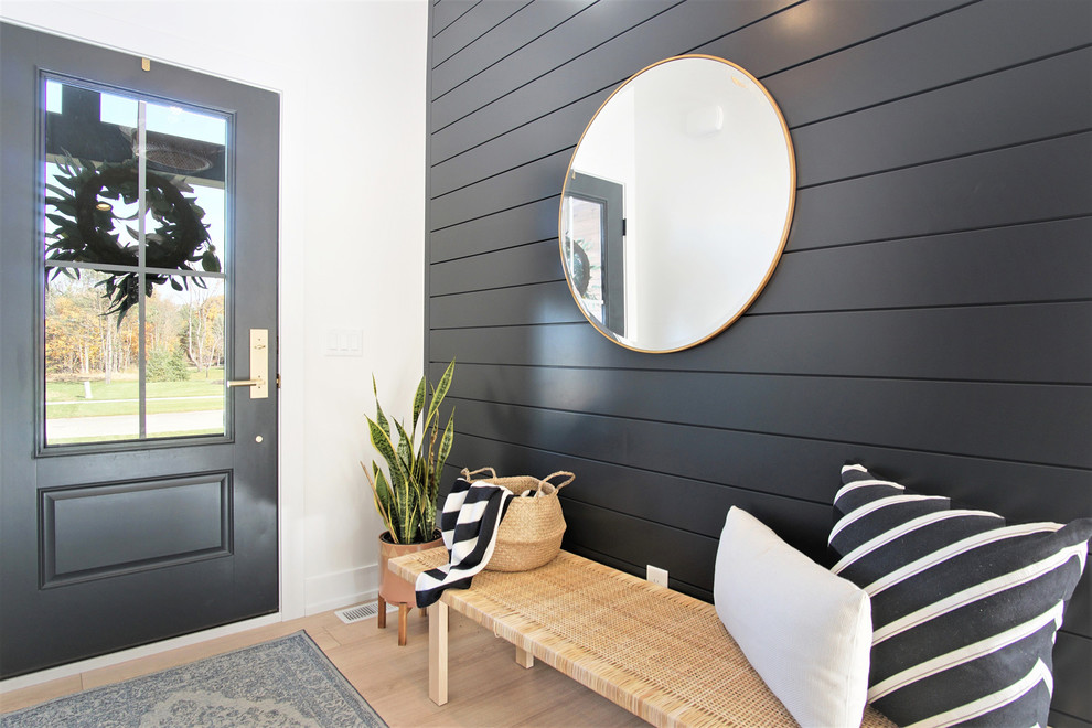 This is an example of a medium sized scandi hallway in Grand Rapids with black walls, light hardwood flooring, a single front door, a black front door and beige floors.