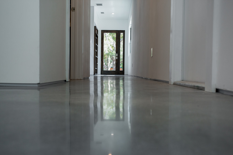 Idee per un ampio corridoio moderno con pareti bianche, pavimento in cemento, una porta singola e una porta in legno scuro