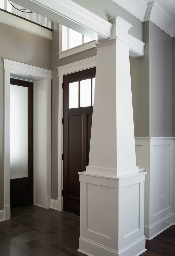 Réalisation d'une entrée tradition avec un mur gris, un sol en marbre, une porte simple et une porte en bois foncé.