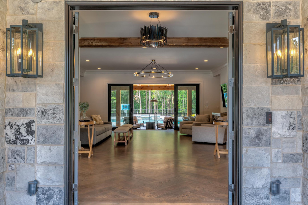 Foto di un ampio ingresso minimalista con pareti bianche, pavimento in legno massello medio, una porta a due ante, una porta nera, pavimento marrone e travi a vista