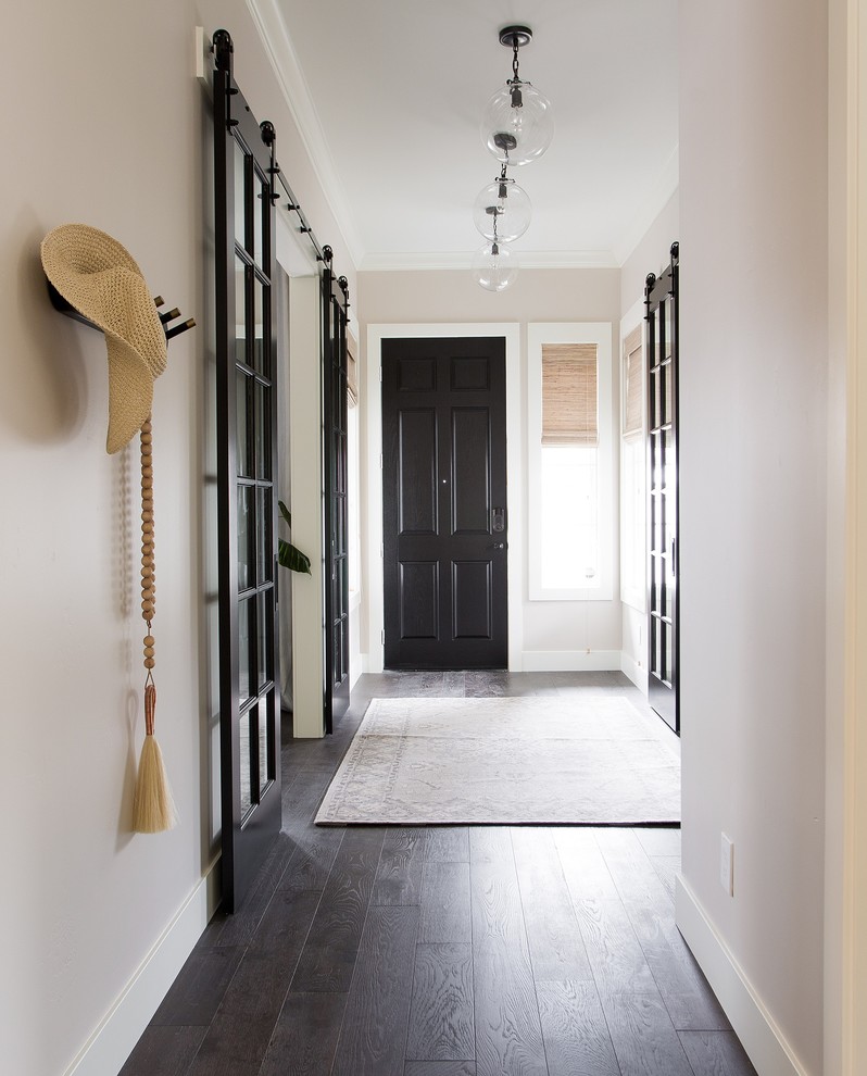 Immagine di un corridoio tradizionale con pareti beige, parquet scuro, una porta singola, una porta nera e pavimento marrone