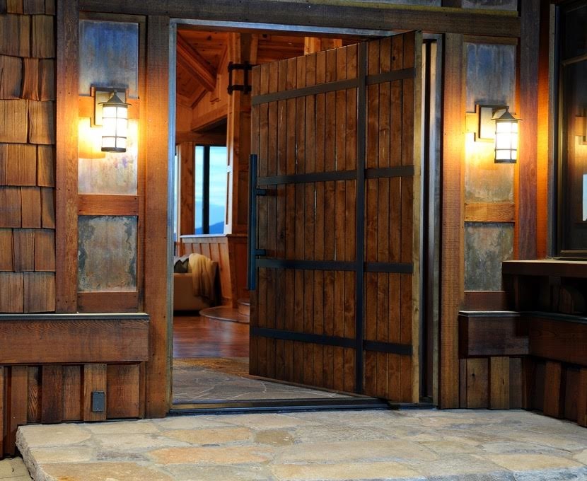 Réalisation d'une porte d'entrée chalet de taille moyenne avec un mur marron, une porte pivot et une porte en bois brun.
