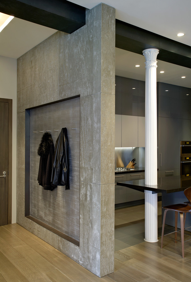 Modern inredning av en stor entré, med ljust trägolv, en enkeldörr och grå väggar