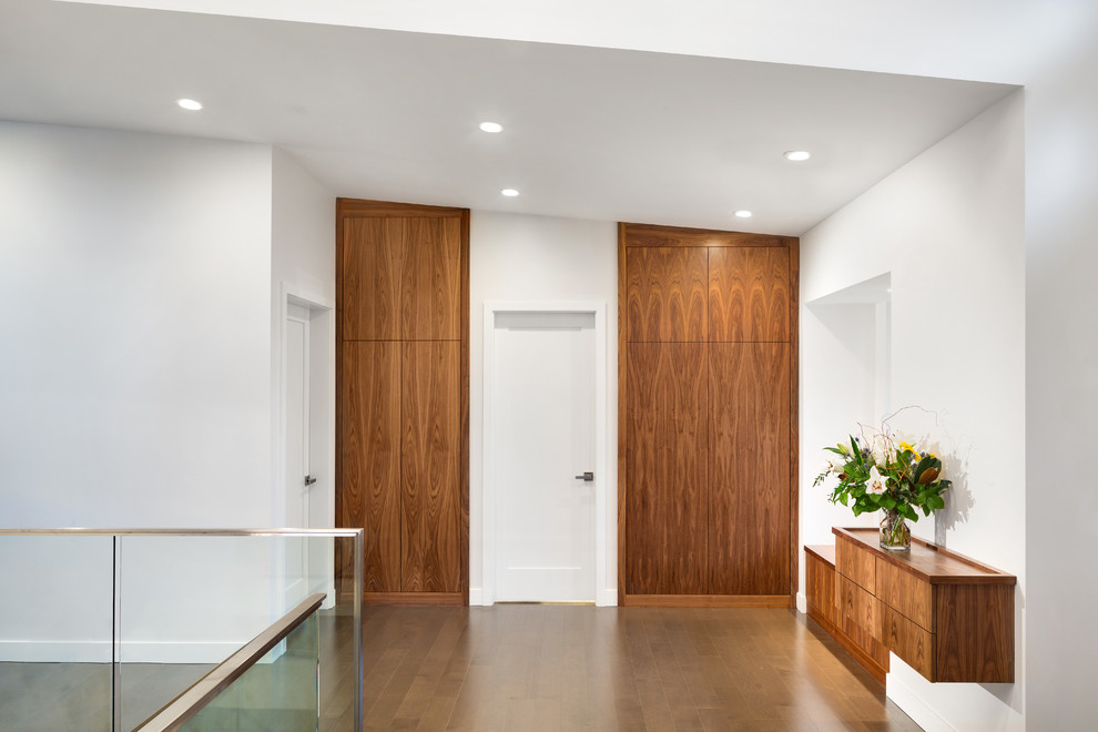 Стильный дизайн: большая входная дверь в стиле модернизм с белыми стенами, темным паркетным полом, двустворчатой входной дверью и входной дверью из светлого дерева - последний тренд