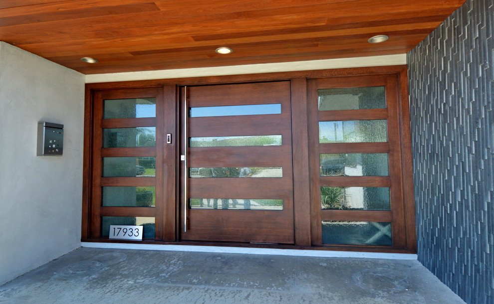Exemple d'une porte d'entrée avec un mur blanc, sol en béton ciré, une porte pivot, une porte en bois brun et un sol gris.
