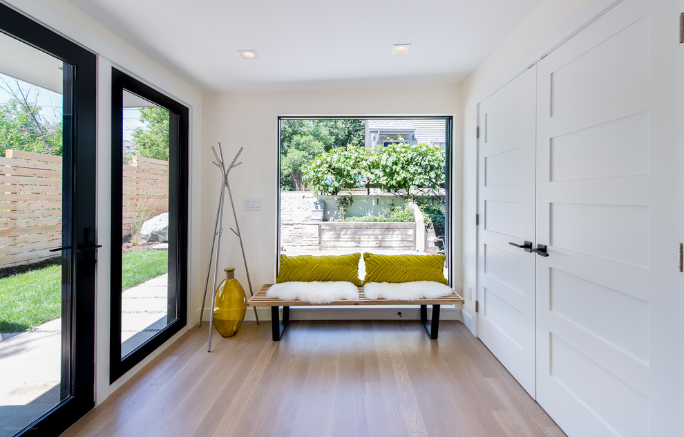Inspiration pour une entrée design de taille moyenne avec un vestiaire, un mur blanc, un sol en bois brun, une porte simple et une porte en verre.