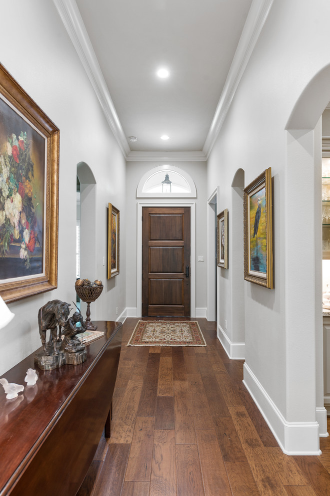Inspiration for a traditional hallway in Austin with grey walls, dark hardwood flooring, a single front door, a dark wood front door and brown floors.