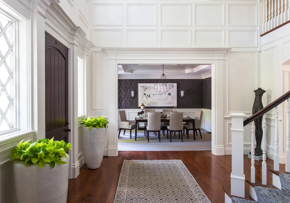 Example of a huge classic dark wood floor and brown floor foyer design in Boston with white walls