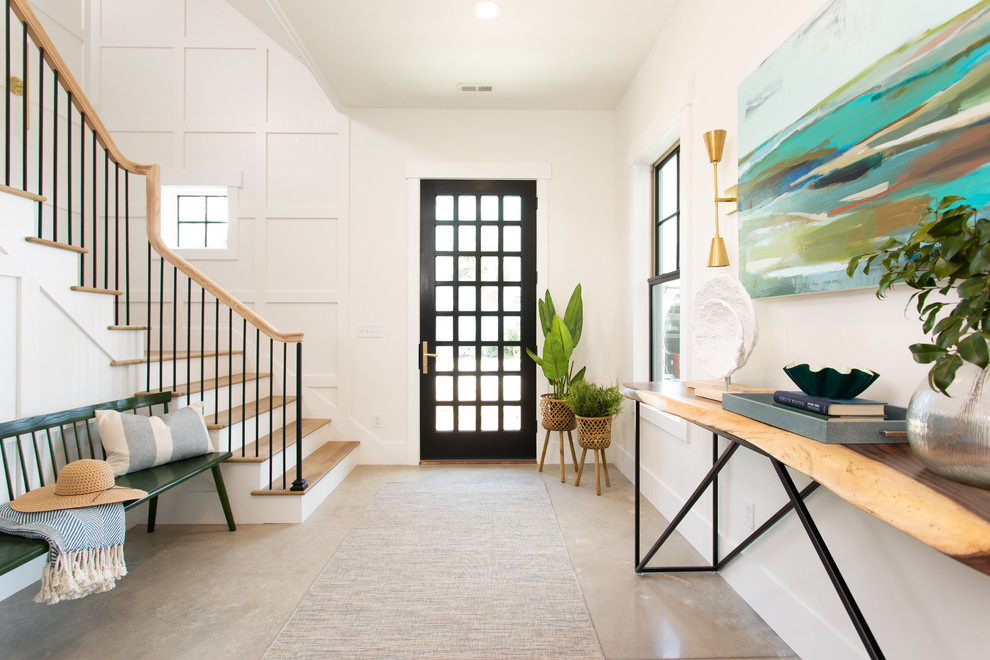 На фото: фойе в морском стиле с белыми стенами, бетонным полом, одностворчатой входной дверью и черной входной дверью