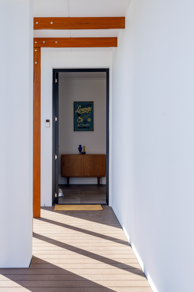 ゴールドコーストにある高級な中くらいなトロピカルスタイルのおしゃれな玄関ドア (白い壁、無垢フローリング、木目調のドア、茶色い床) の写真