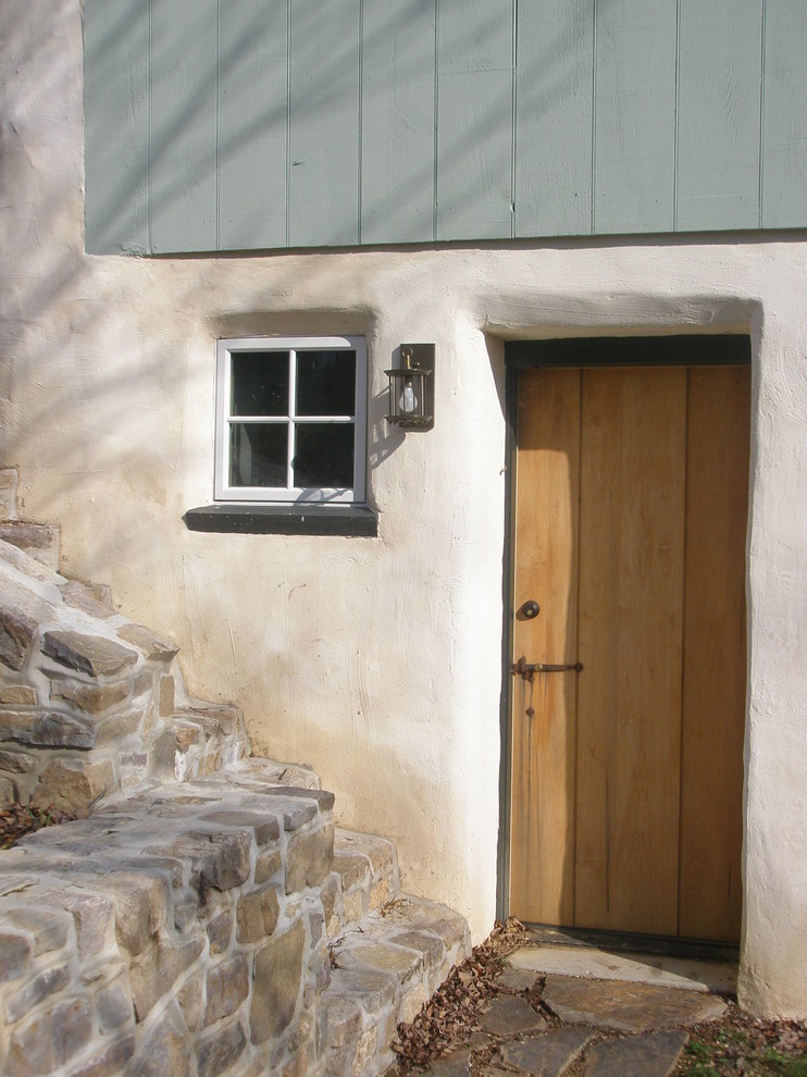 This is an example of a bohemian front door in Philadelphia with a single front door and a medium wood front door.