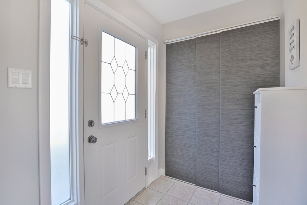 This is an example of a medium sized modern front door in Toronto with grey walls, light hardwood flooring, a single front door and a white front door.