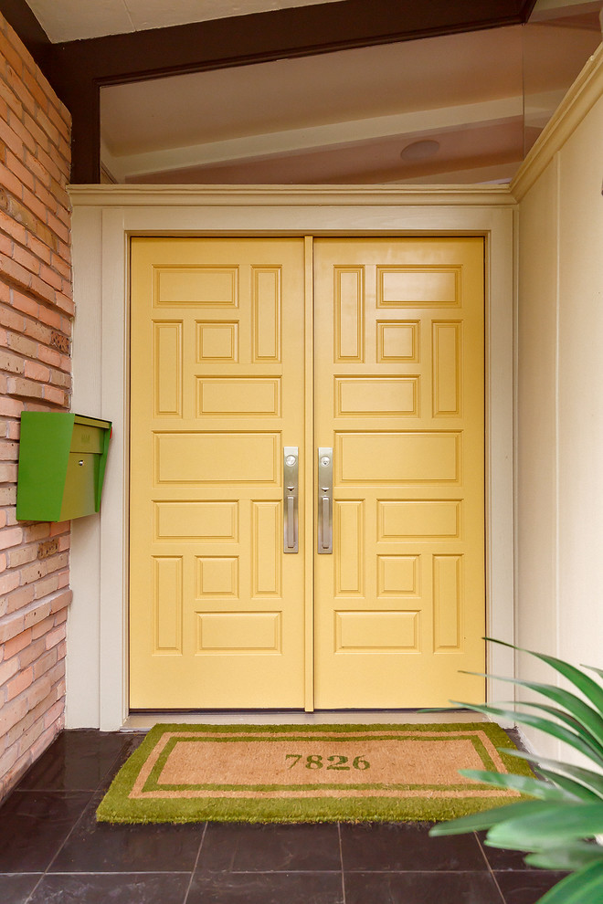 Imagen de puerta principal retro grande con paredes beige, suelo de pizarra, puerta doble, puerta amarilla y suelo gris
