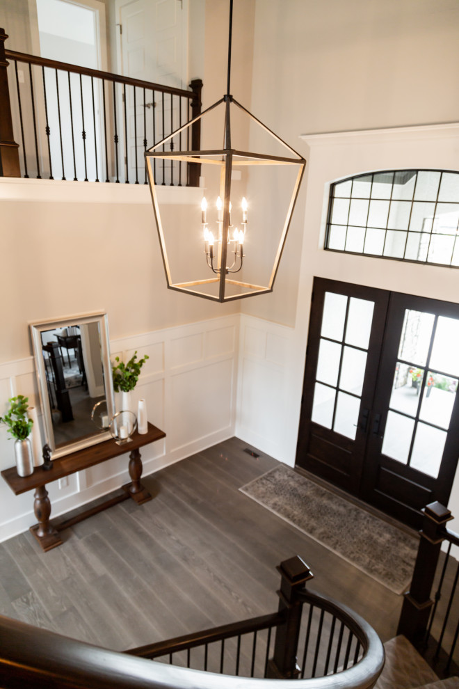 Inspiration for a large transitional medium tone wood floor and gray floor entryway remodel in Kansas City with beige walls and a black front door