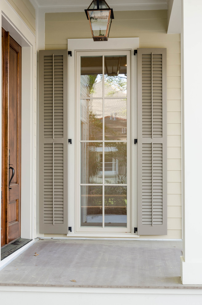 Réalisation d'une porte d'entrée tradition de taille moyenne avec un mur beige, une porte double et une porte en bois brun.