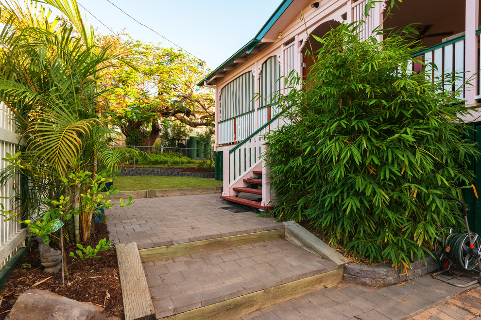 Example of an island style entryway design in Brisbane with pink walls and a red front door