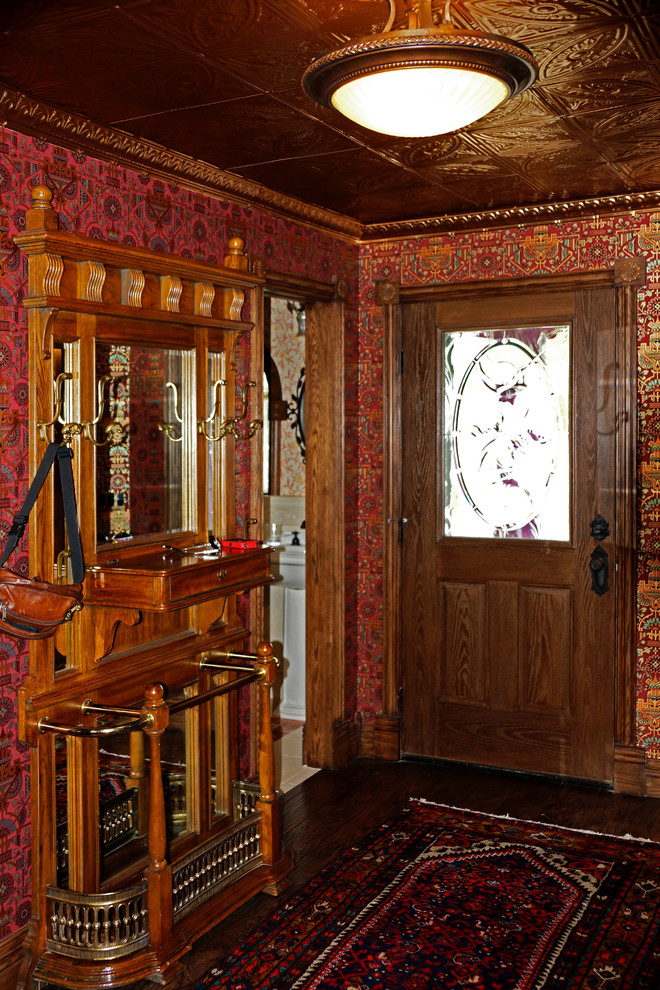 Inspiration pour un petit hall d'entrée traditionnel avec un mur rouge, parquet foncé, une porte simple et une porte en bois foncé.