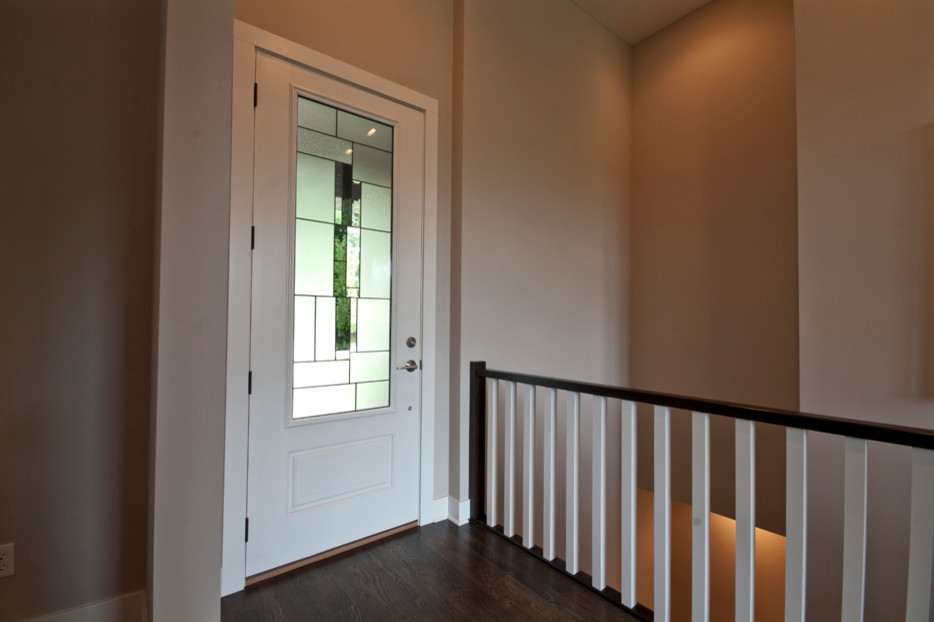 Modernes Foyer mit beiger Wandfarbe, dunklem Holzboden, Einzeltür und weißer Haustür in Sonstige