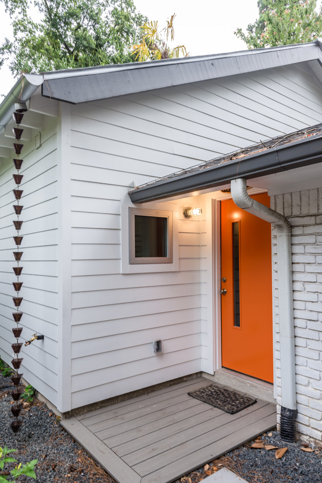 Exempel på en liten modern hall, med vita väggar och en orange dörr