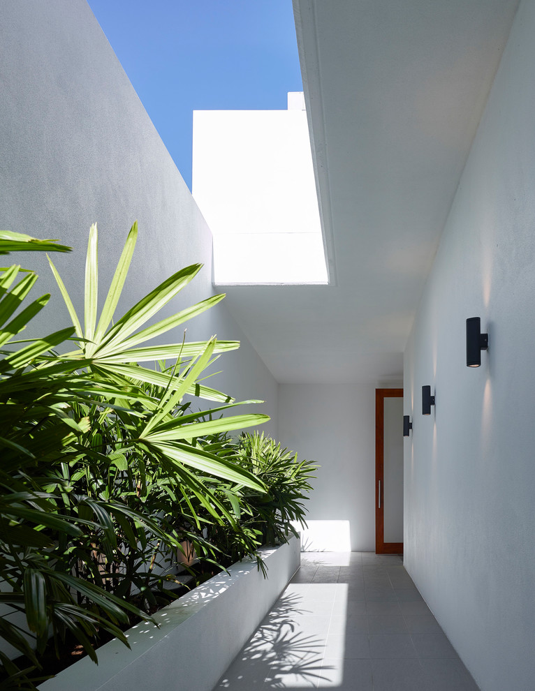 Photo of an expansive contemporary front door in Brisbane with white walls, porcelain flooring, a pivot front door, a medium wood front door and grey floors.