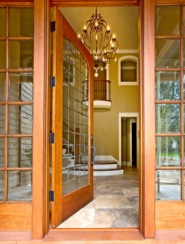 Amerikansk inredning av en mycket stor ingång och ytterdörr, med beige väggar, travertin golv, en enkeldörr och en brun dörr