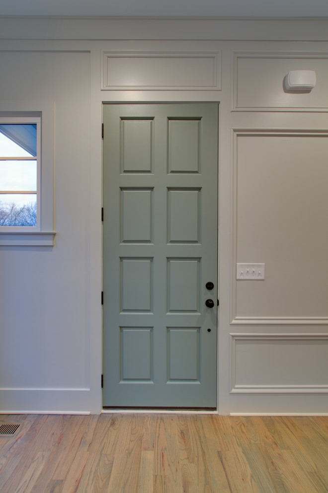 Exempel på en mellanstor klassisk foajé, med vita väggar, ljust trägolv, en enkeldörr och en grön dörr