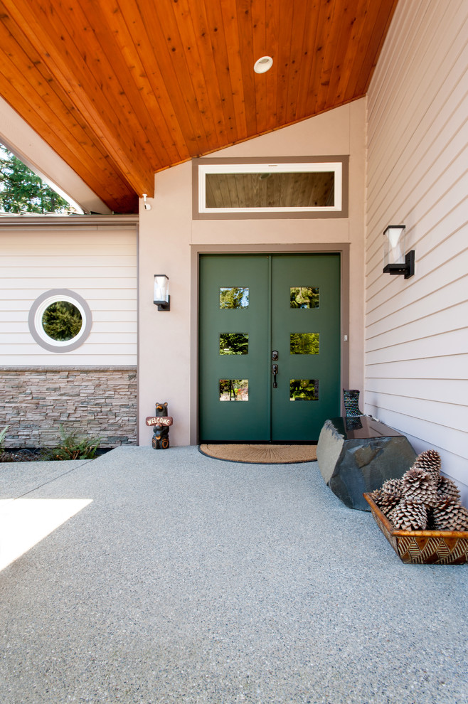 Immagine di una grande porta d'ingresso bohémian con pareti beige, pavimento in cemento, una porta a due ante e una porta verde