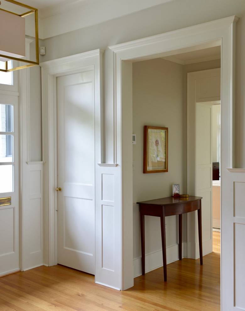 Idées déco pour une grande entrée classique avec un couloir, un mur gris, un sol en bois brun, une porte simple, une porte blanche et un sol marron.