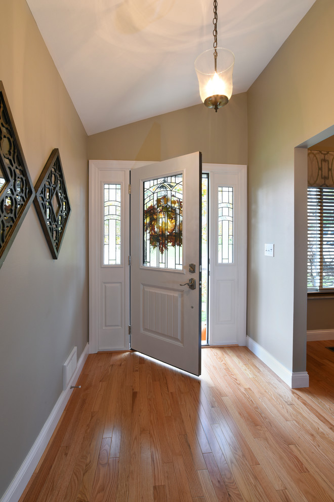 Cette photo montre une entrée chic de taille moyenne avec un couloir, un mur marron, parquet clair, une porte simple, une porte blanche et un sol beige.
