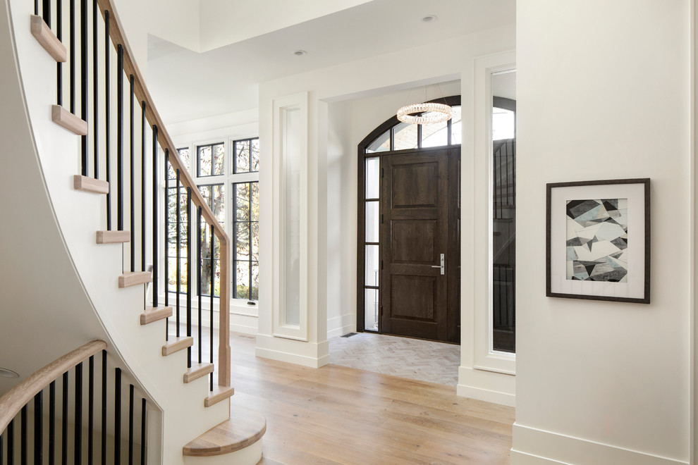 Réalisation d'une entrée tradition avec un mur blanc, parquet clair, une porte double et une porte noire.